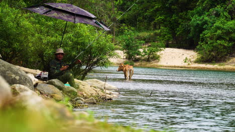 Man-from-Rag-Lai-tribe-fishing-with-rod-in-countryside-river-in-Vietnam