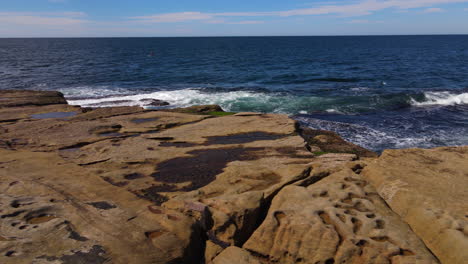 sliding-drone-shot-of-rocks-being-lapped-with-waves