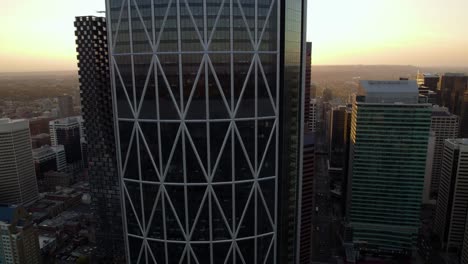 Aerial-view-in-front-of-the-Bow-building-in-downtown-Calgary,-sunset-in-Canada---ascending,-drone-shot