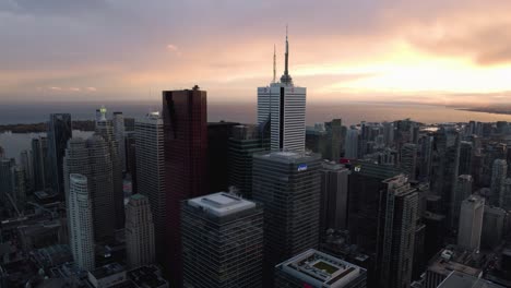 Aerial-view-of-skyscrapers-in-downtown-Toronto,-revealing-the-CN-tower,-dramatic-sunset-in-Ontario,-Canada---ascending,-drone-shot