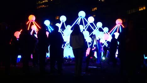 Silhouette-people-interact-with-illuminated-Affinity-neuron-artwork,-Chavasse-park,-Liverpool-River-of-light