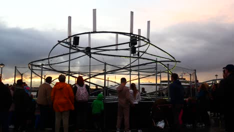 Öffentlichkeit-Interagiert-Mit-Beleuchtetem-Spiralförmigem-Lichtschleifer-Neuron-Kunstwerk,-Liverpool-Pier-Head-River-Of-Light-Event-Mit-Dramatischem-Sonnenuntergang