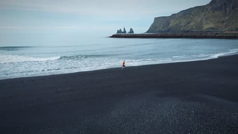 Tracking-Shot-Of-sportive-Man-Running-On-Magical-Sandy-Black-Beach,-Iceland