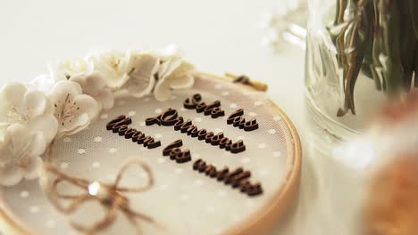 Slow-motion-handheld-panning-shot-of-a-wedding-cake-with-a-font-of-chocolate,-bow-and-white-roses-decorated-on-a-white-table