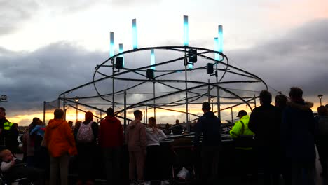 Public-interact-with-illuminated-spiral-light-looper-neuron-artwork,-Liverpool-pier-head-river-of-light-sunset-event