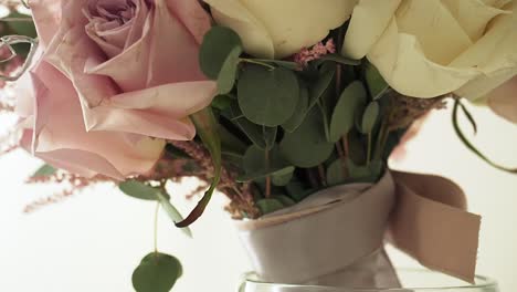 Slow-motion-ascending-close-up-shot-of-a-wedding-bouquet-in-a-vase-with-pink-and-yellow-roses-with-ornaments-and-decorations-for-the-wedding-day