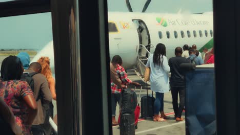 African-Passengers-Boarding-a-Air-Cote-d'Ivoire-Bombardier-DHC-8-Q400-Airplane-at-Abidjan-Félix-Houphouët-Boigny-International-Airport,-view-from-Airport-Bus-Windows