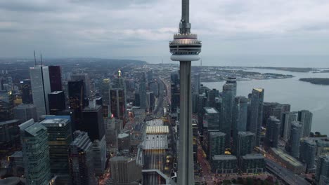 Aerial-view-of-the-CN-Tower-and-the-Union-Station,-gloomy-evening-in-Toronto,-Canada---pull-back,-drone-shot