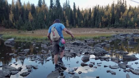 Hiker-on-pond-skipping-rocks-Kananaskis-Alberta-Canada