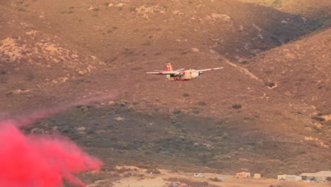 Firefighting-plane-drops-pink-chemical-water-at-rugged-hill-terrain-to-extinguish-wildfire-in-California