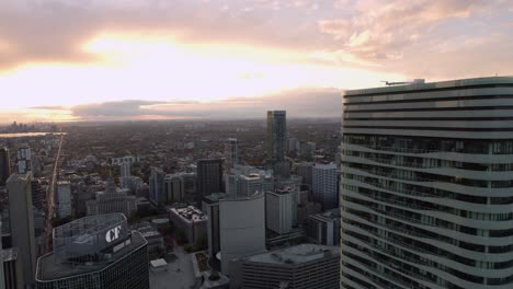 Aerial-view-of-the-cityscape-of-downtown-Toronto,-Canada,-during-sunset---pan,-drone-shot