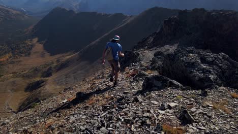 Hiker-running-by-cliff-over-valley-followed-Kananaskis-Alberta-Canada