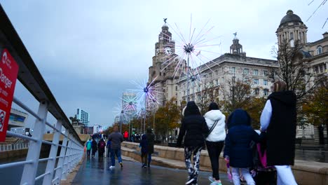 People-sightseeing-around-flashing-neon-electric-dandelions-artwork-at-Liverpool-pier-head-river-of-light-event-on-Liver-building-waterfront