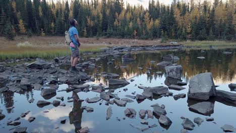 Hiker-on-pond-rocks-looking-around-Kananaskis-Alberta-Canada