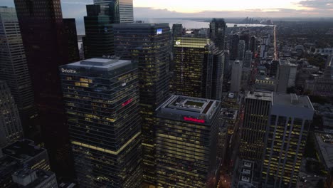Aerial-view-close-to-illuminated-skyscrapers-in-downtown-Toronto,-during-dusk---tracking,-drone-shot