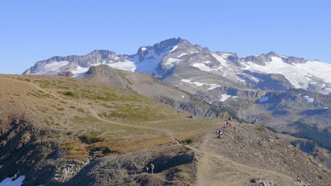 Wanderer-Auf-Dem-Wanderweg-An-Einem-Sonnigen-Tag-In-Whistler,-British-Columbia,-Kanada-Mit-Schneebedeckten-Bergen-Und-Blauem-Himmelshintergrund