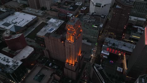 Aerial-view-away-from-the-illuminated-Carew-tower,-dusk-in-USA---reverse,-tilt,-drone-shot