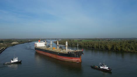 Aerial-View-Of-Tug-Boats-Assisting-Sea-Prajna-Bulk-Carrier-Along-Oude-Maas-In-Puttershoek