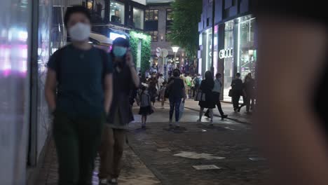 People-walking-on-the-pedestrian-between-shopping-centers-at-night-in-Hong-Kong