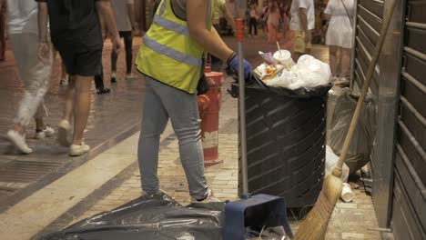 Female-street-cleaner-emptying-overflowing-waste-bin