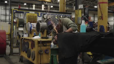 Blue-collar-worker-welding-metal-in-workshop,-sparks-flying-in-slow-motion