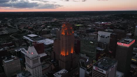 Aerial-view-circling-around-the-illuminated-Carew-tower,-colorful-sundown-in-Ohio,-USA