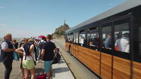People-Standing-And-Waiting-On-The-Roadside-Bus-Stop-Area-At-Mont-Saint-Michel,-France