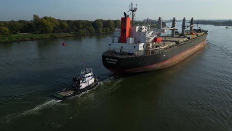 Tug-Boat-Attached-To-Stern-of-Sea-Prajna-Bulk-Carrier-As-It-Navigates-Along-Oude-Maas
