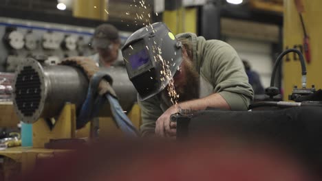 Blue-collar-worker-grinding-metal-in-industrial-workshop,-slow-motion