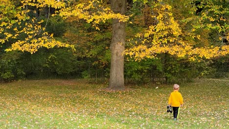 Süßer-Blondie-Junge,-Der-Auf-Gefallenen-Herbstblättern-Läuft-Und-Mit-Seinem-Spielzeug-In-Der-Natur-Spielt