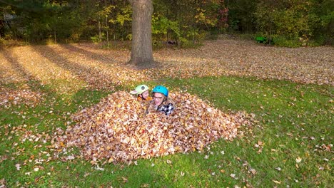 Zwei-Kinder-Springen-In-Der-Herbstsaison-Freudig-In-Einen-Großen-Laubhaufen