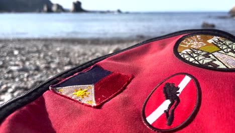 Red-Eastpack-style-Bag-With-Scuba-Diving-Flag-Patch,-Philippines-Flag-by-the-seaside