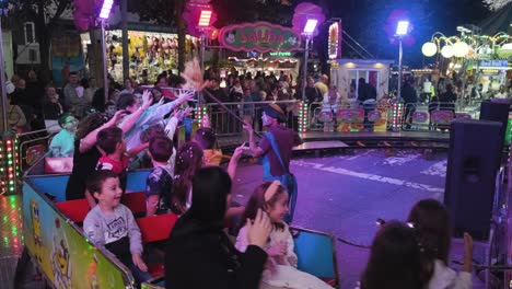 Carnaval-De-San-Froilán-En-La-Noche,-Ciudad-De-Lugo,-España,-Gente-Divirtiéndose-Montando-Un-Tren-De-Juguete
