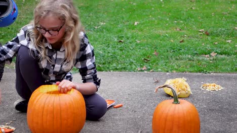 Blondie-Mädchen,-Das-Glücklich-Mit-Ihrer-Hand-Orange-Kürbis-An-Halloween-Schnitzt