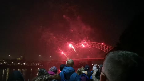 Crowd-watch-colourful-fireworks-exploding-on-Silver-Jubilee-bridge,-Widnes