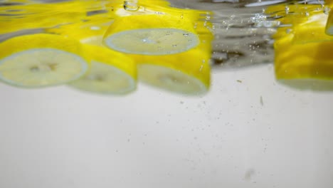Hinzufügen-Von-Zitronenscheiben-In-Süßwasser-Mit-Blasen,-Natürliches-Zitrusaroma