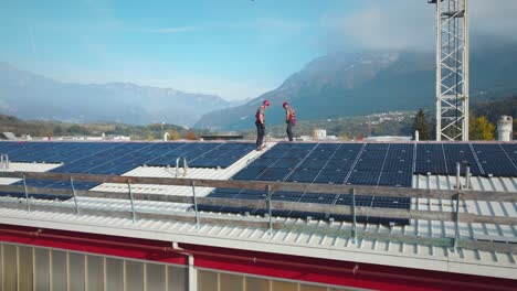 Dos-Trabajadores-Montando-Paneles-Solares-En-El-Techo-Superior-De-Un-Edificio-Industrial