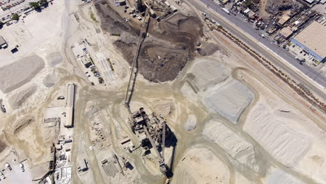Open-pit-mining-quarry-for-sand-and-gravel---aerial-tilt-up-to-reveal-Sun-Valley-City,-California