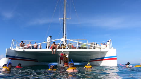 People-enjoying-swimming-in-ocean-and-moving-to-catamaran-sail-boat-|Tourists-moving-in-to-Boat-after-snorkeling-adventure-|-Catamaran-boat-ride-in-middle-of-Caribbean-sea