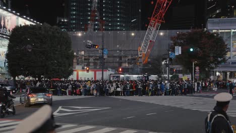 Shibuya-Kreuzung-Bei-Nacht,-Menschenmassen,-Die-Darauf-Warten,-Mit-Polizeiwachen-überquert-Zu-Werden