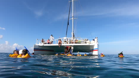Tourist-with-life-jackets-and-snorkeling-masks-moving-inside-the-catamaran-sail-boat-in-middle-of-the-sea-|-Swimming-and-snorkeling-tour-experience-in-ocean-|-Catamaran,-tourism,-snorkeling,-Adventure