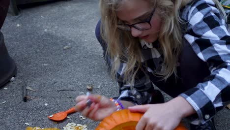Cute-Blondie-Girl-Painting-With-Black-Pen-On-Orange-pumpkin,-Halloween