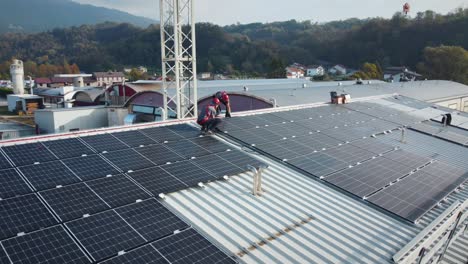 Dos-Trabajadores-Montando-Paneles-Solares-En-El-Techo-Superior-De-Un-Edificio-Industrial