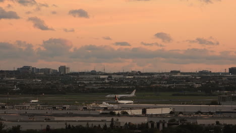 Busy-airport-of-Toronto-with-orange-sunset-sky,-static-time-lapse-view