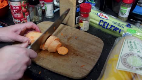 Person-Cutting-With-Big-Knife-Vegetables-Into-Slices-On-Wooden-Board,-Close-Up