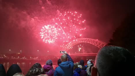 People-watch-colourful-fireworks-exploding-on-Silver-Jubilee-bridge,-Widnes