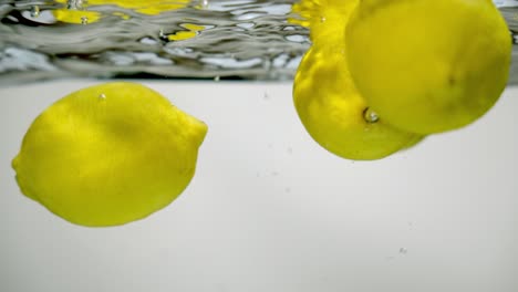 Vier-Ganze-Zitronen-Zitrusfrüchte-In-Frisches,-Sauberes-Sprudelwasser-Getaucht