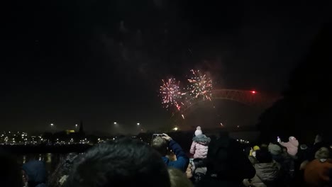 Crowd-watch-colourful-fireworks-festival-exploding-on-Silver-Jubilee-bridge,-Widnes