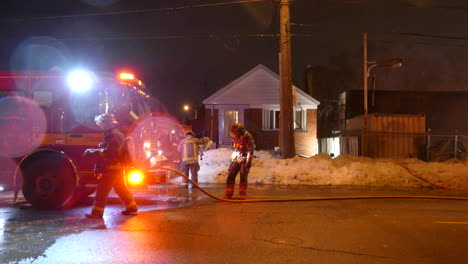 Ein-Team-Von-Feuerwehrleuten-Drängte-Sich-Um-Die-Vorderseite-Eines-Feuerwehrautos-Am-Ort-Eines-Wohnhausbrandes-In-Der-Nacht,-Toronto,-Kanada