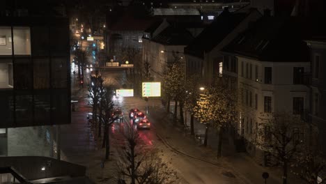 Busy-road-junction-with-traffic-at-night-in-Stromgaten-street-beside-Grieg-concert-hall-in-Bergen-Norway---Static-timelapse-with-long-exposure-and-motion-blur-on-moving-car-lights